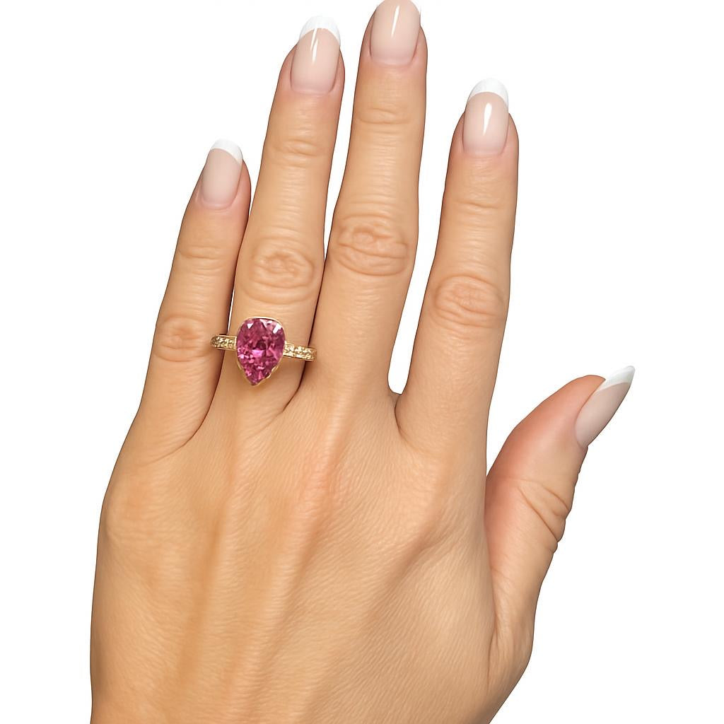 Anel em prata com banho de ouro amarelo com pedra de 5 quilates de safira rosa com duas gotas de 80 pontos nas laterais.